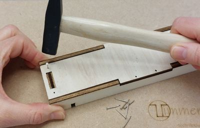 Kind timmert houten onderdelen vast van het knutselpakket Kundige Knikkervanger