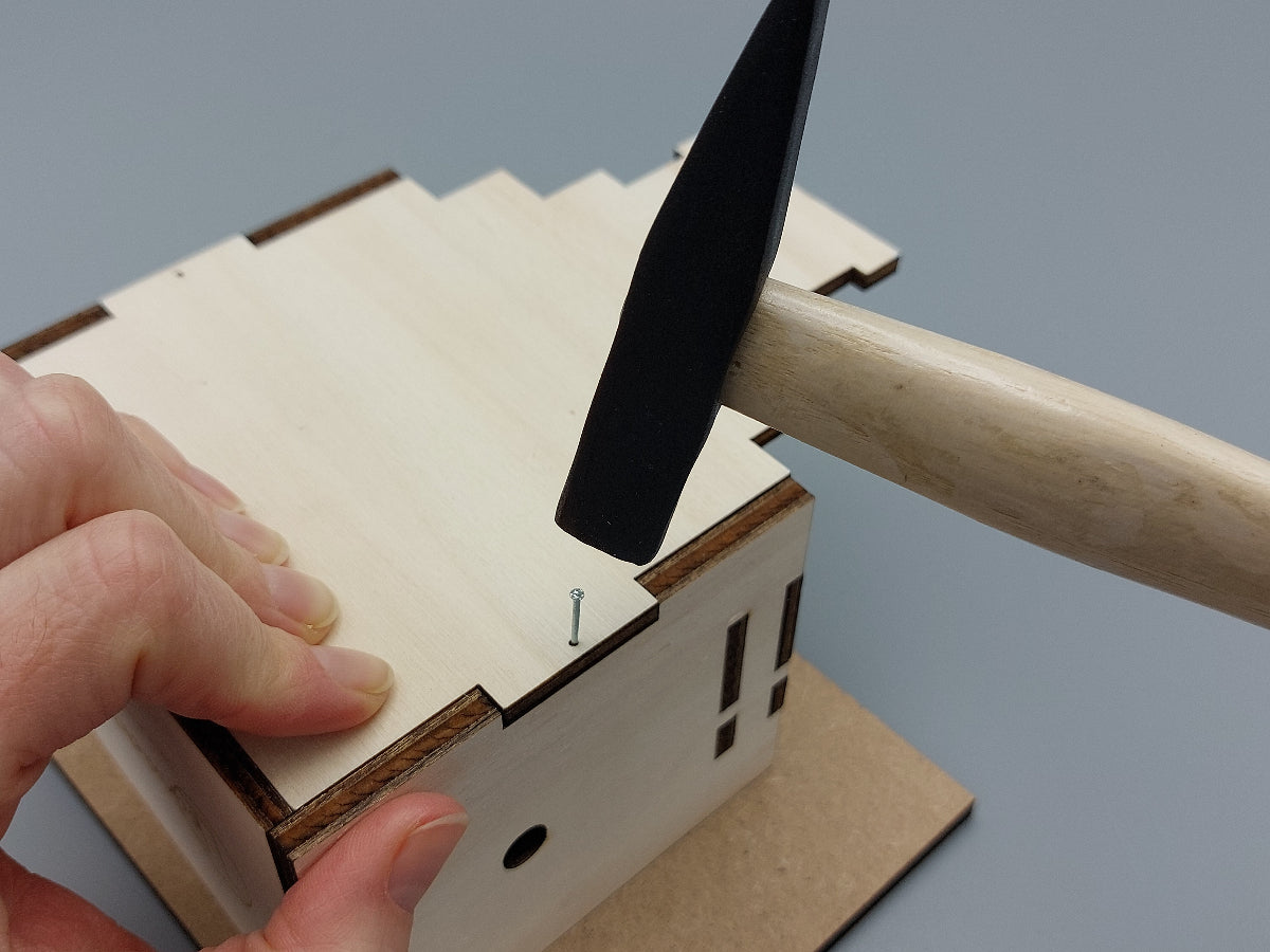 Knutselen: timmeren van het houten huis van Coole Klaus, de Kerstman-automaton. Leren hameren, veilig en leuk voor 6–12 jaar. Gemaakt in Nederland.