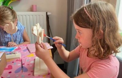 Meisje in roze t-shirt schildert met concentratie haar knutselpakket tijdens een creatief kinderfeestje – techniek, plezier en knutselen gecombineerd in een leerzame activiteit