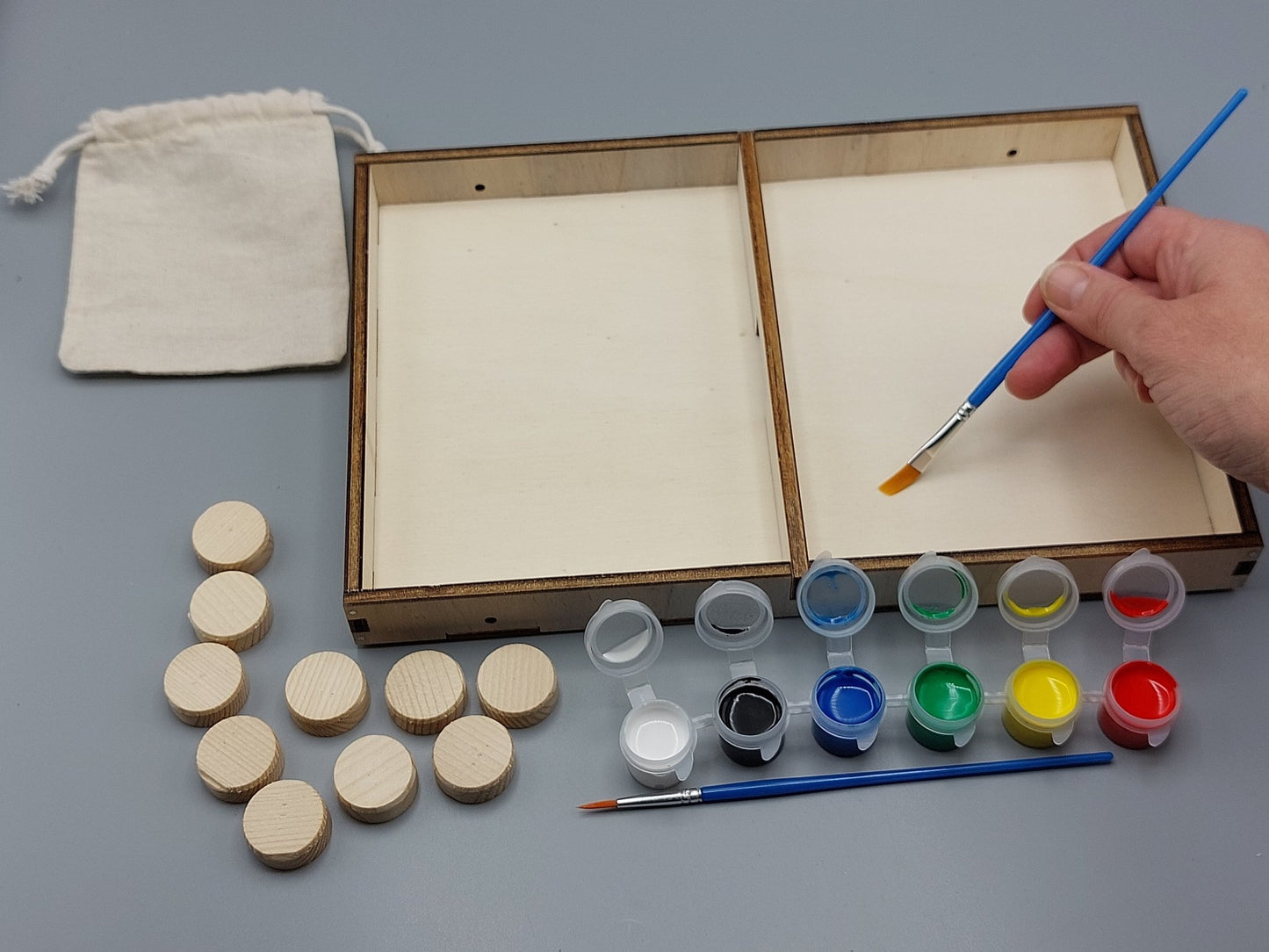 Knutselen voor kinderen met knutselpakket Schuivende Schijven – kind schildert zijn project in vrolijke, creatieve kleuren