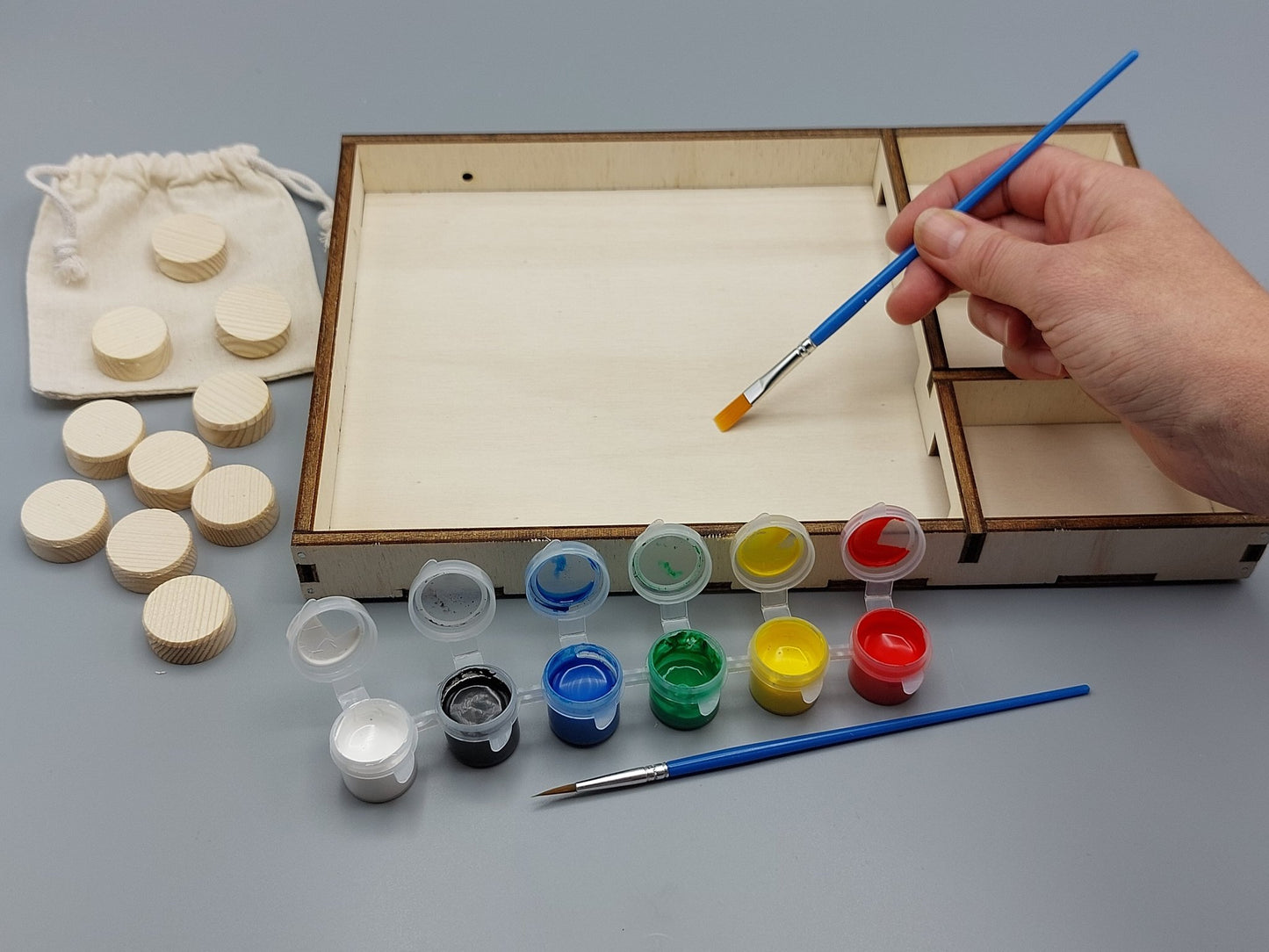 Knutselen voor kinderen met knutselpakket Sjezend Sjoelen–Sjoelbak – kind schildert zijn project in vrolijke, creatieve kleuren