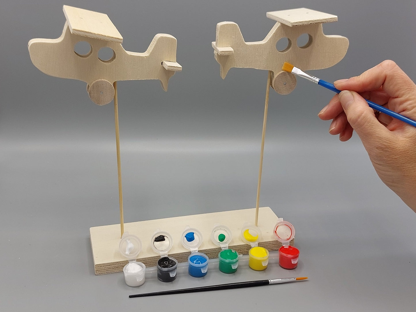 Knutselen voor kinderen met knutselpakket Vlugge Vliegtuigen – kind schildert zijn project in vrolijke, creatieve kleuren