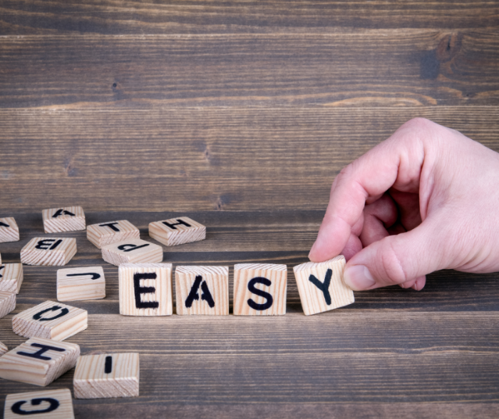 Hand legt houten blokjes in de juiste volgorde om het woord 'easy' te vormen – symbool voor het gemak van de kant-en-klare knutselpakketten van TechniekLudiek